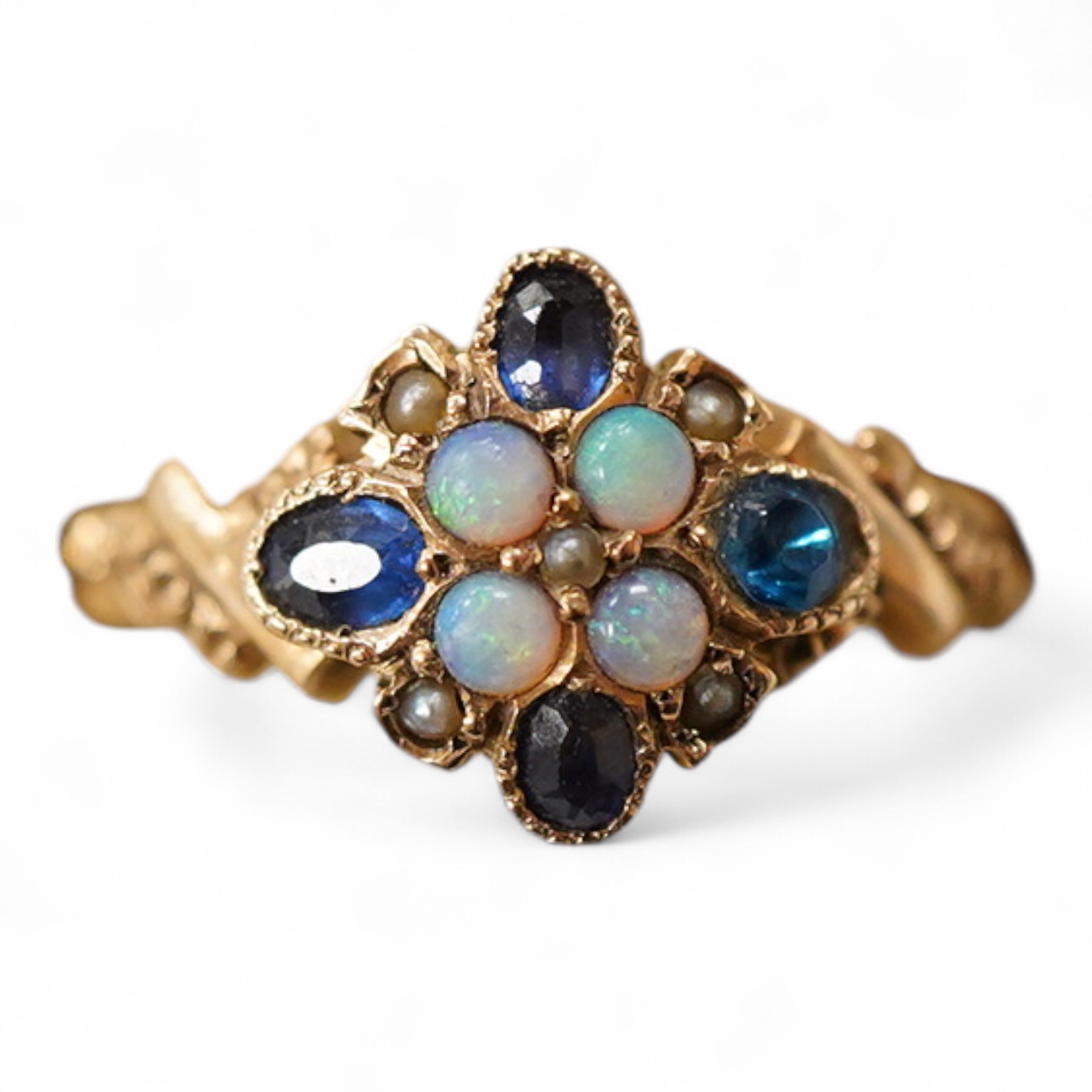 A late Victorian yellow metal, sapphire, opal and seed pearl cluster set dress ring, (one stone a paste replacement), size N, gross weight 2.2 grams.